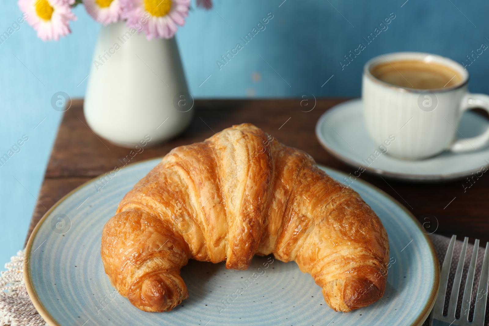 Photo of Delicious fresh croissant served with coffee on wooden table, closeup