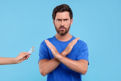 Stop smoking concept. Man refusing cigarettes on light blue background