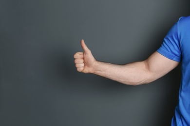 Photo of Young man showing thumb sign on color background