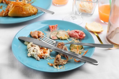 Photo of Dirty plate with leftovers on white tablecloth after party