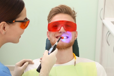 Photo of Professional dentist working with patient in modern clinic. Teeth whitening