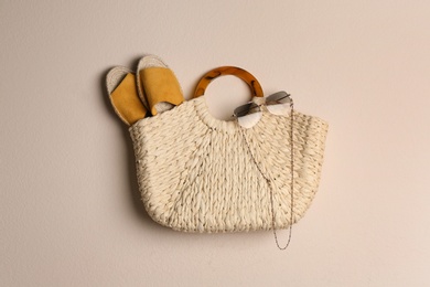 Photo of Elegant woman's straw bag with shoes and sunglasses on beige background, top view