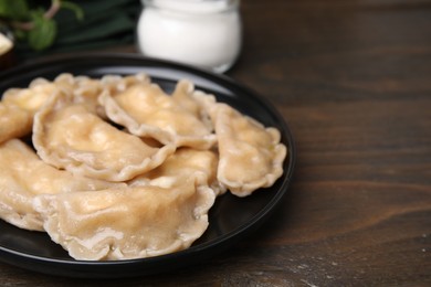 Photo of Plate of delicious dumplings (varenyky) with cottage cheese on wooden table, closeup