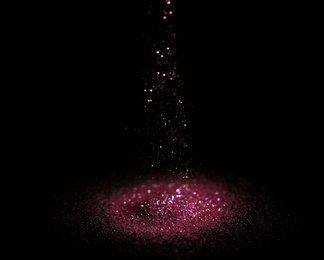 Photo of Sprinkling rose glitter on black background, bokeh effect
