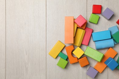 Photo of Colorful building blocks on wooden floor, flat lay. Space for text
