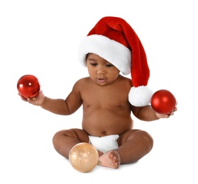 Photo of Cute African-American baby wearing Santa hat with Christmas decorations on white background
