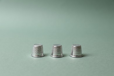 Photo of Three thimbles on pale olive background. Thimblerig game