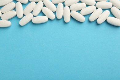 Vitamin pills on light blue background, flat lay. Space for text