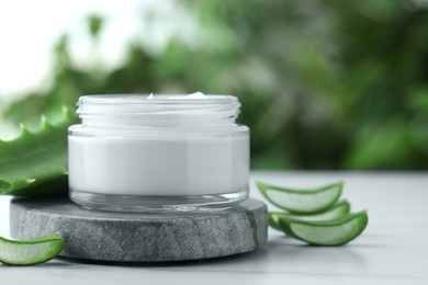 Photo of Jar with cream and cut aloe leaf on white table, closeup. Space for text