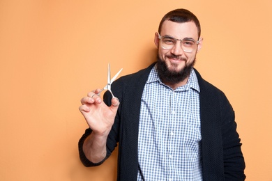 Professional hairdresser with scissors on color background