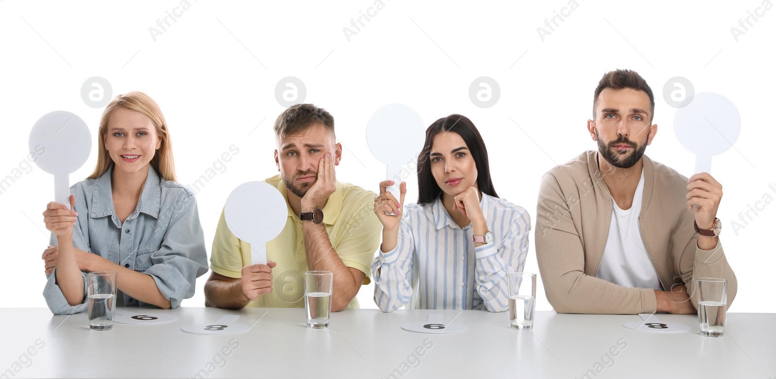 Photo of Panel of judges with different emotions holding blank signs at table on white background. Space for text