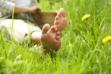 Woman sitting barefoot on green grass outdoors, closeup