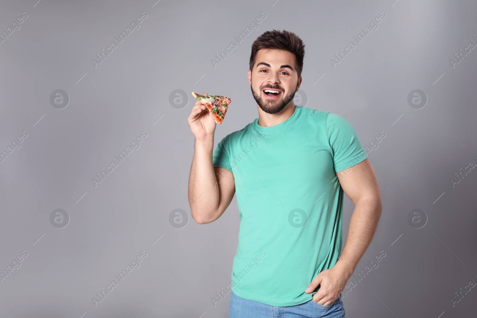 Photo of Handsome man with pizza on grey background, space for text