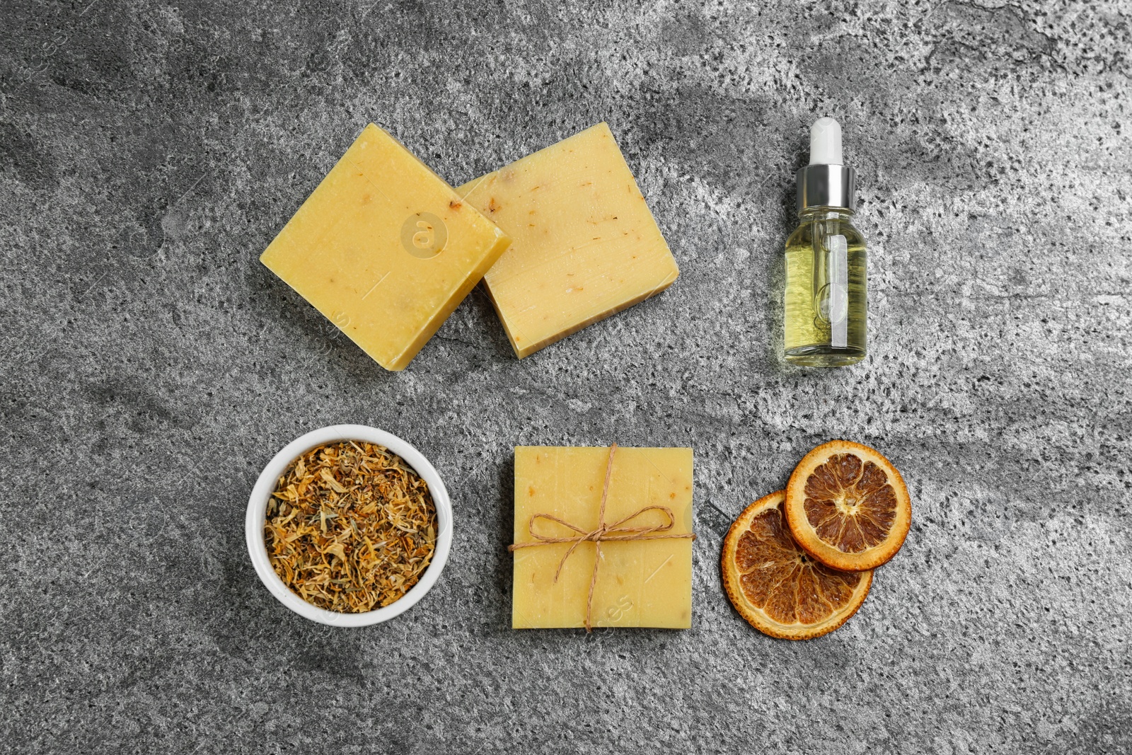 Photo of Flat lay composition with natural handmade soap and ingredients on grey stone table