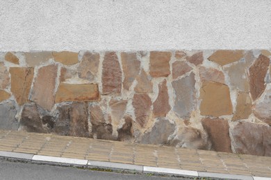 Empty concrete wall with stone fragments on city street