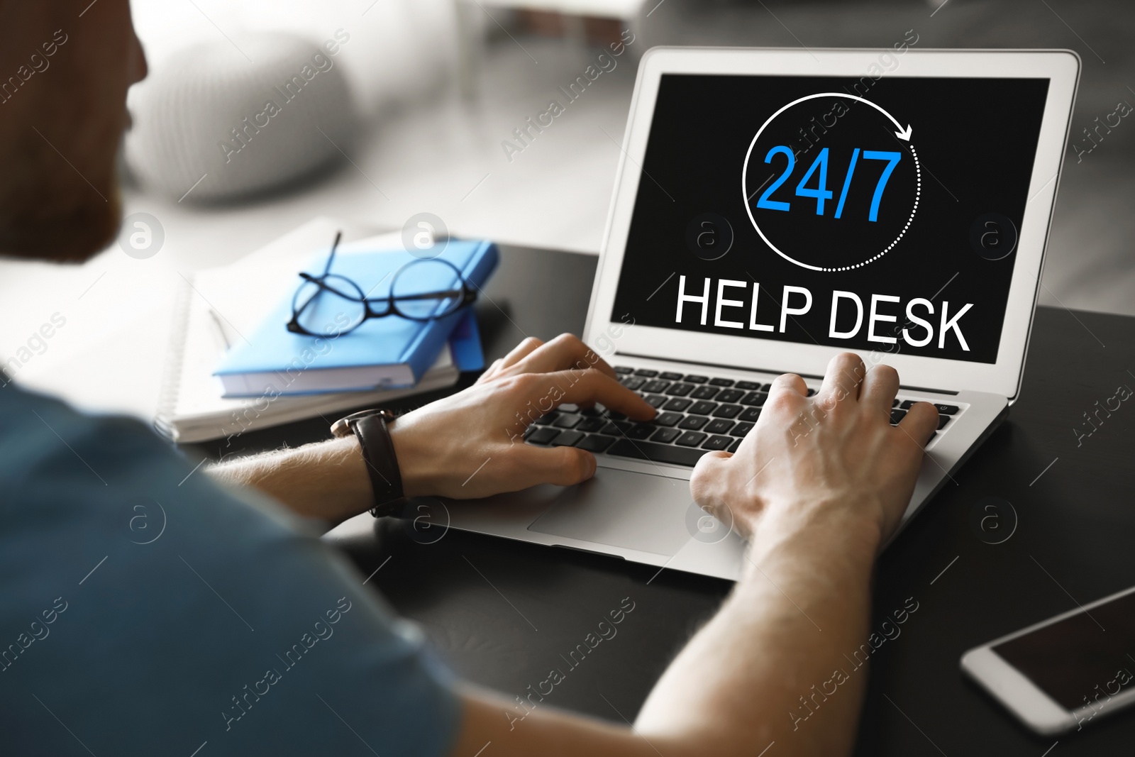 Image of Man using laptop at table indoors, closeup. Help desk service