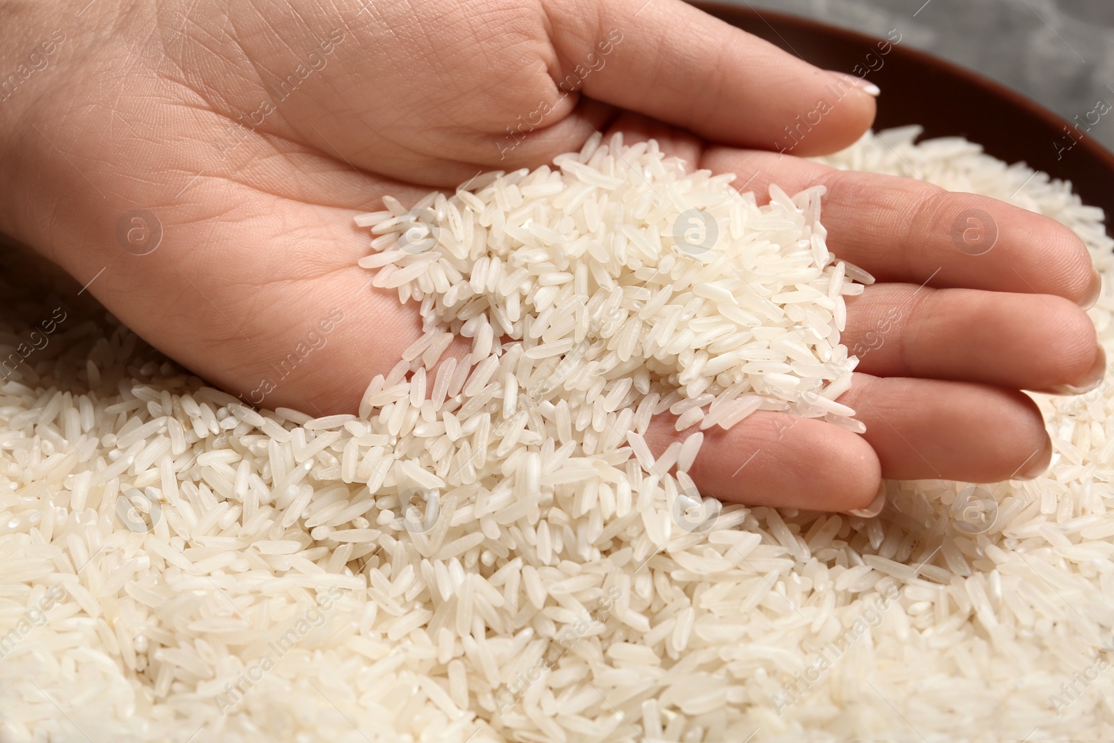 Photo of Woman holding grains near plate with rice on table, closeup