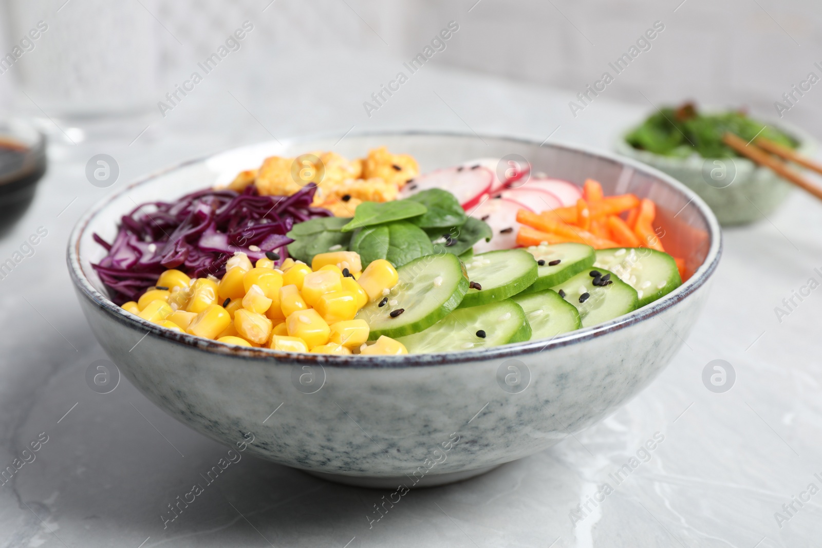 Photo of Delicious salad with chicken, vegetables and spinach on grey marble table, closeup