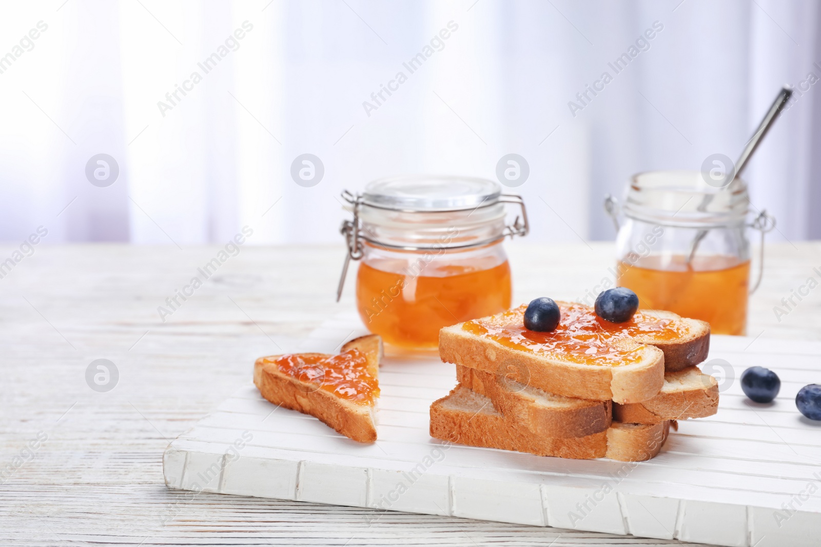 Photo of Toasts with jam and berries on wooden board, closeup