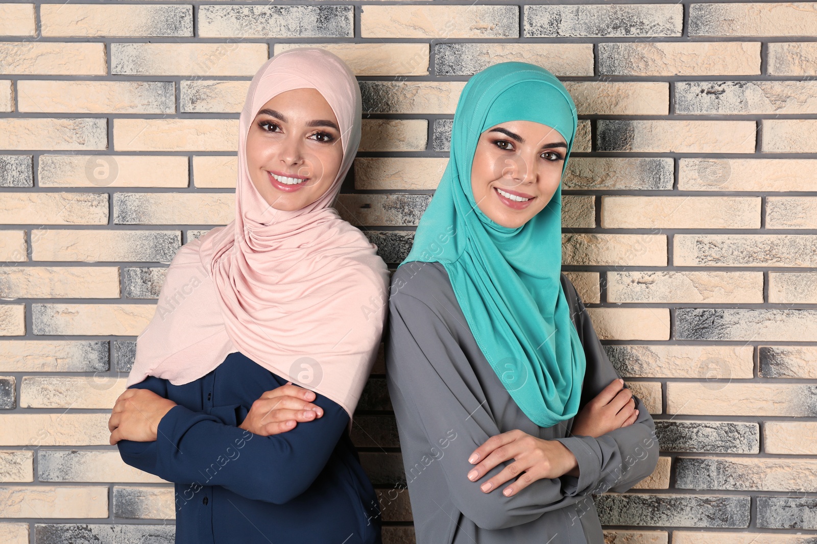 Photo of Portrait of young Muslim women in hijabs against brick wall