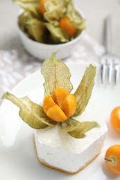 Photo of Delicious dessert decorated with physalis served on table, closeup