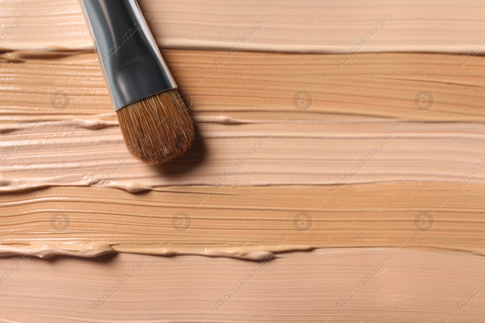 Photo of Samples of skin foundation and makeup brush, top view