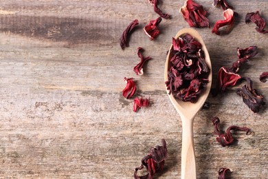 Spoon with dry hibiscus tea on wooden table, flat lay. Space for text