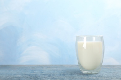 Photo of Glass with fresh milk on table against color background. Space for text