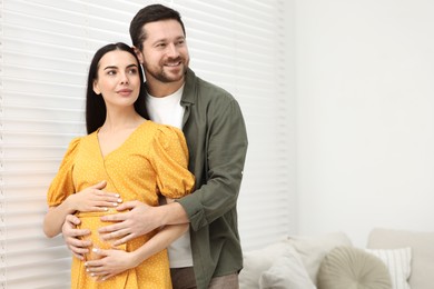 Photo of Pregnant woman with her husband indoors, space for text