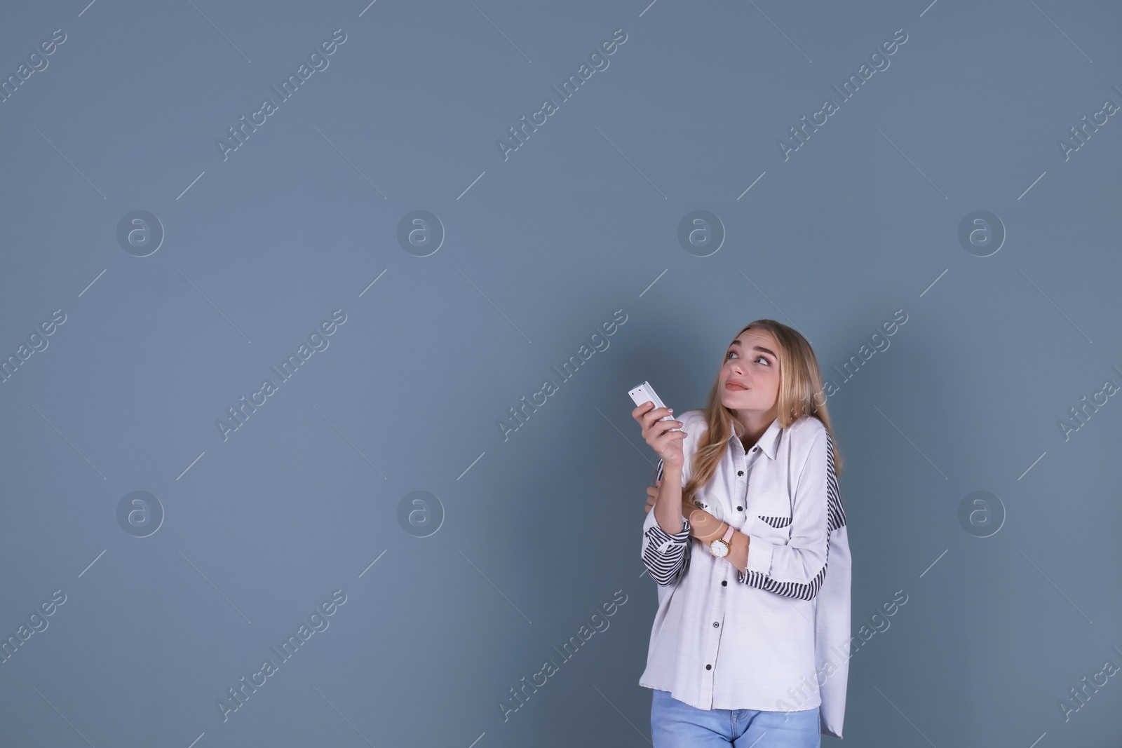 Photo of Young woman operating air conditioner with remote control on color background