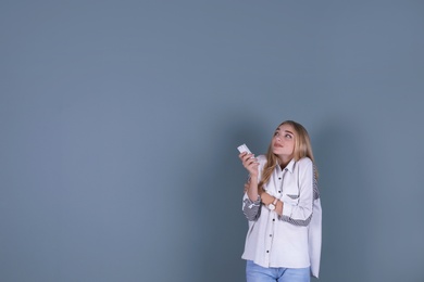 Photo of Young woman operating air conditioner with remote control on color background
