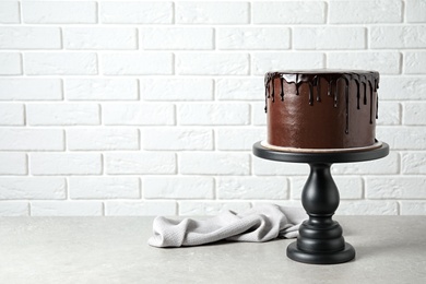 Photo of Freshly made delicious chocolate cake on grey table against white brick wall. Space for text