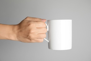 Woman holding ceramic cup on light background. Mock up for design