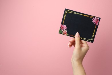 Woman holding blank invitation card on pink background, closeup. Space for text