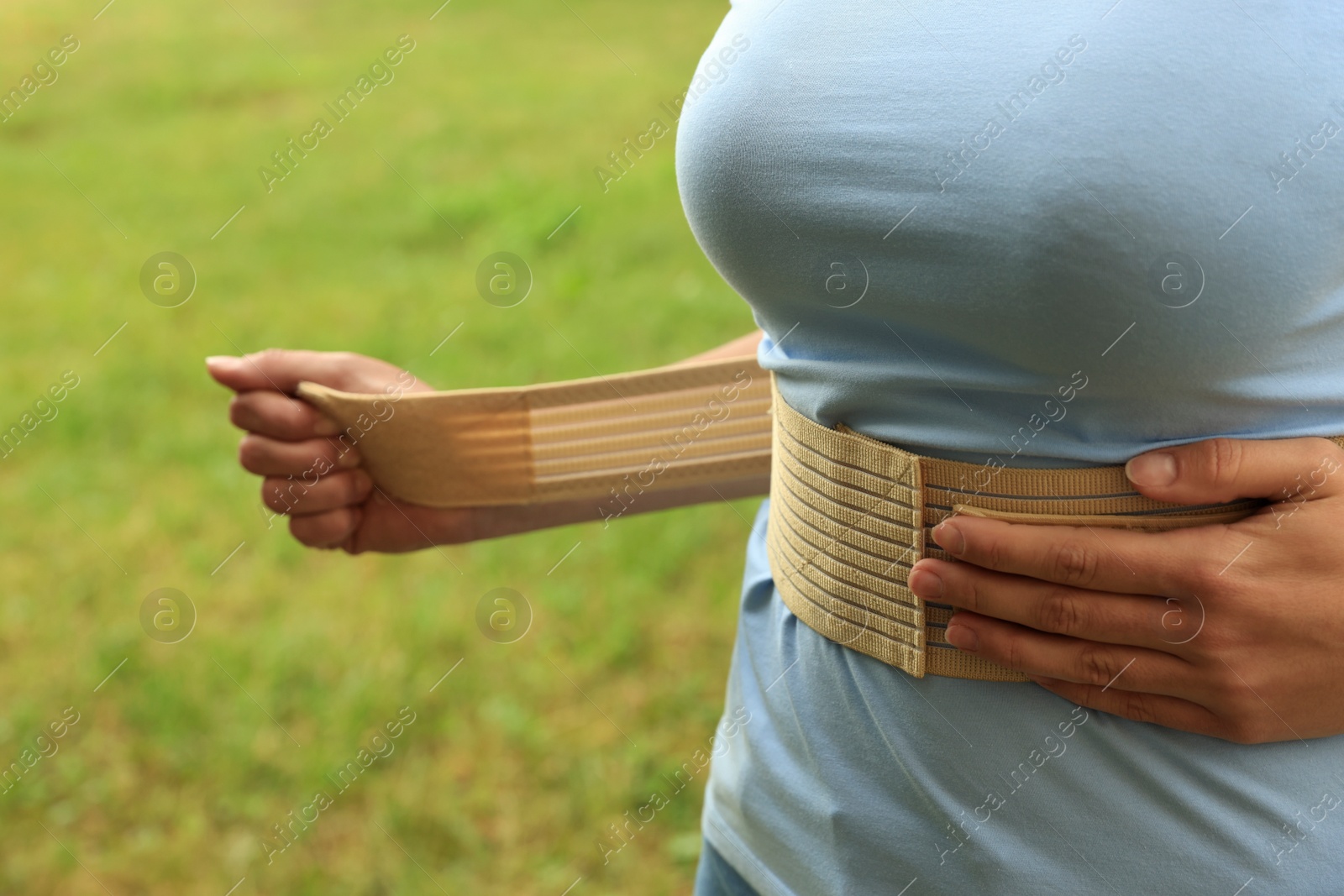 Photo of Closeup view of woman with orthopedic corset on blurred background