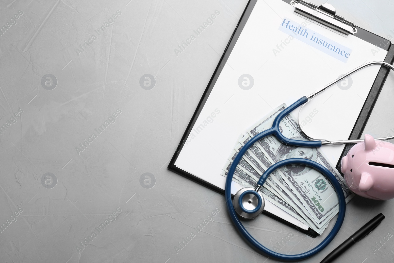 Photo of Medical insurance form with money, stethoscope and piggybank on grey background, flat lay. Space for text