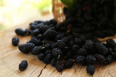 Photo of Heap of delicious ripe black mulberries on wood stump