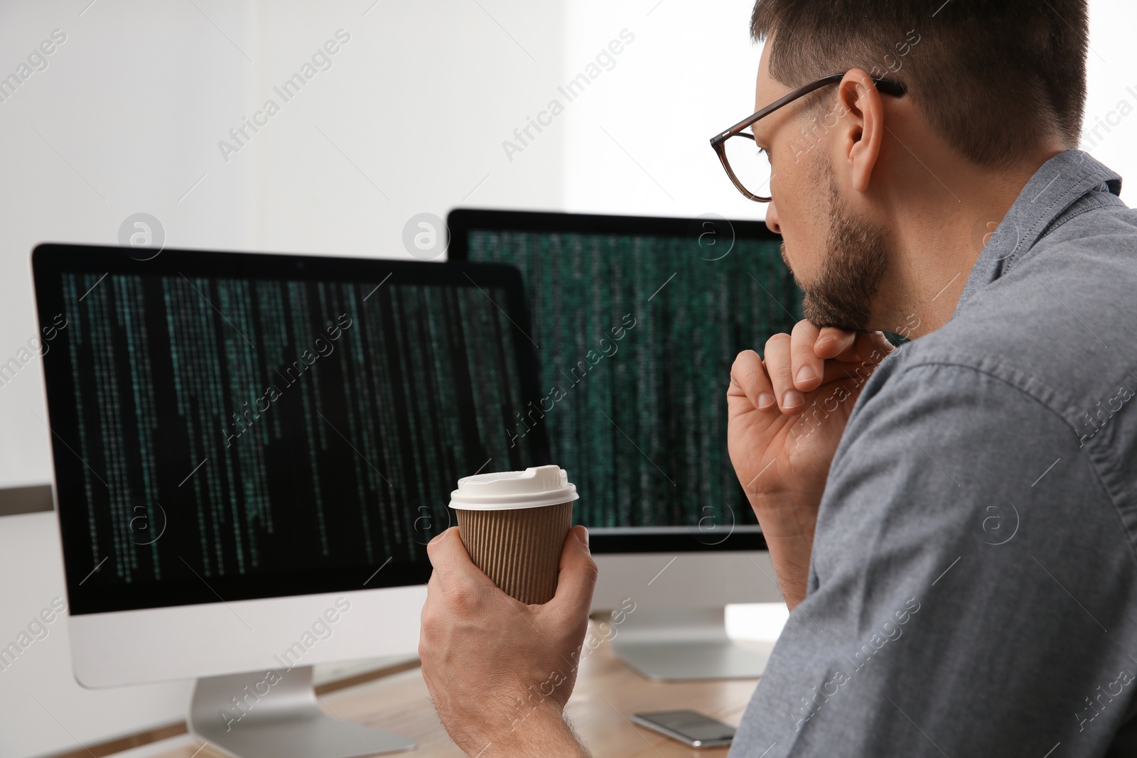 Photo of Programmer with coffee working at desk in office