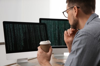 Photo of Programmer with coffee working at desk in office