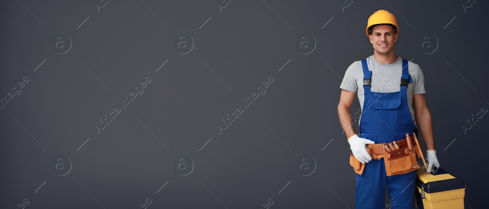 Image of Handsome carpenter with tool box on dark background, space for text. Banner design