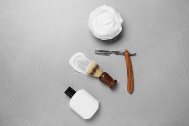 Photo of Set of men's shaving tools and foam on light gray textured table, flat lay