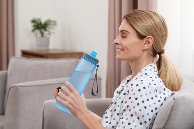 Photo of Woman with bottle of water in armchair at home