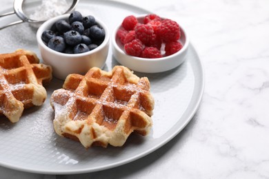 Photo of Delicious Belgian waffles with fresh berries and powdered sugar on white marble table, closeup