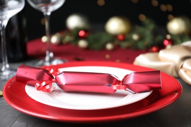 Photo of Bright red Christmas cracker on table, closeup