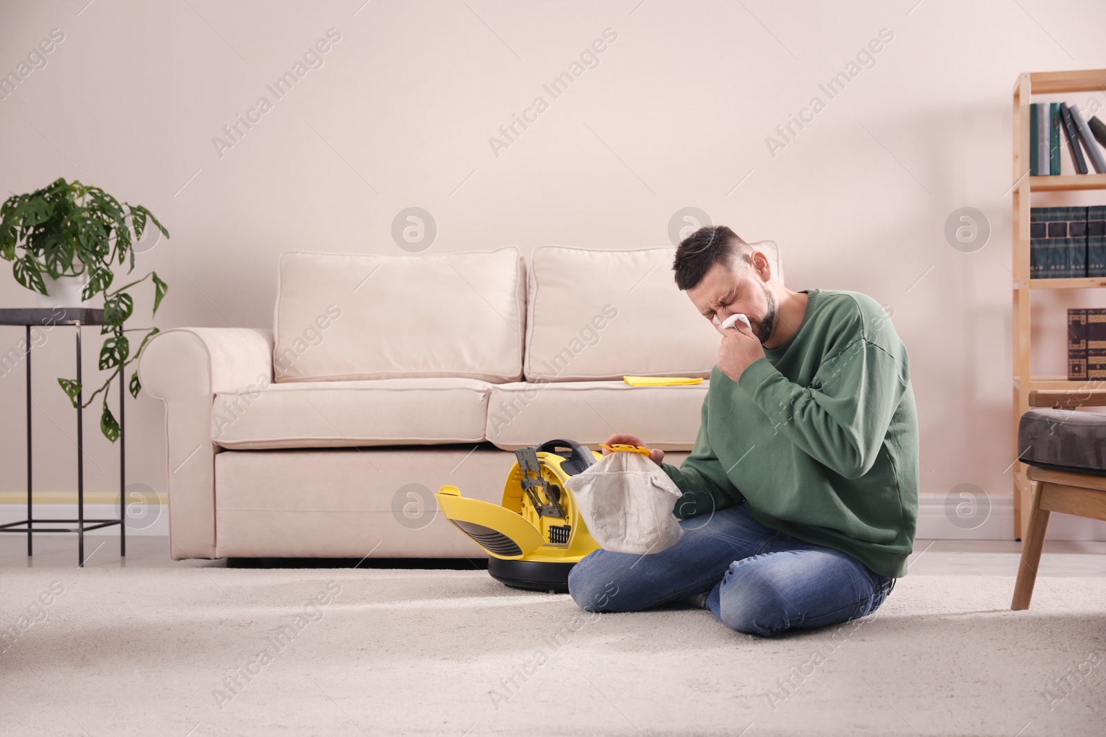 Photo of Man with vacuum cleaner bag suffering from dust allergy at home