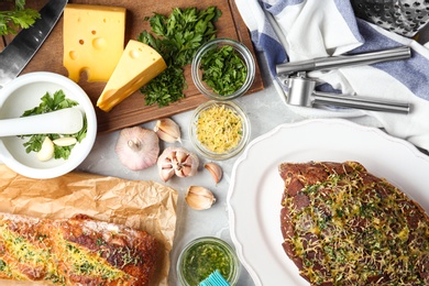 Photo of Loaves of tasty homemade garlic bread with cheese and herbs on grey table, flat lay