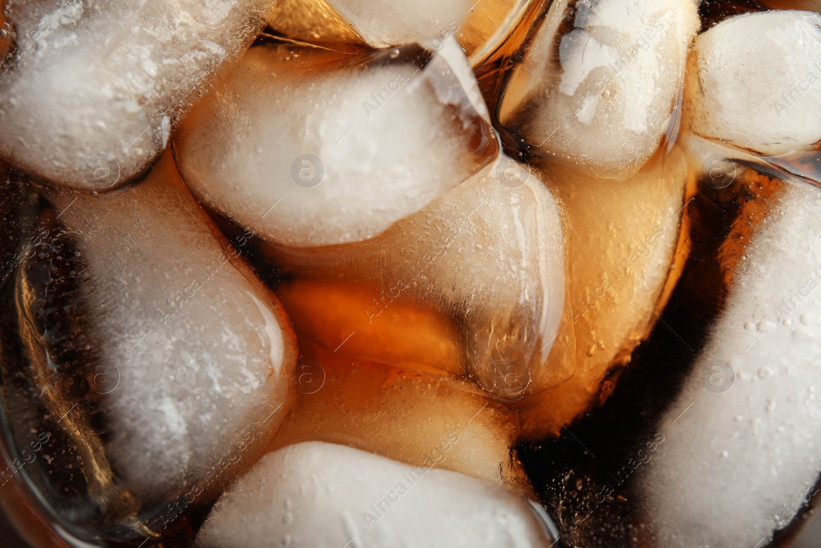 Photo of Closeup view of tasty refreshing cola with ice cubes as background