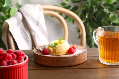 Photo of Tasty vanilla fondant with white chocolate, raspberries and cup of drink on wooden table