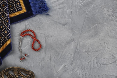 Photo of Flat lay composition with Muslim prayer beads, rug and space for text on grey background