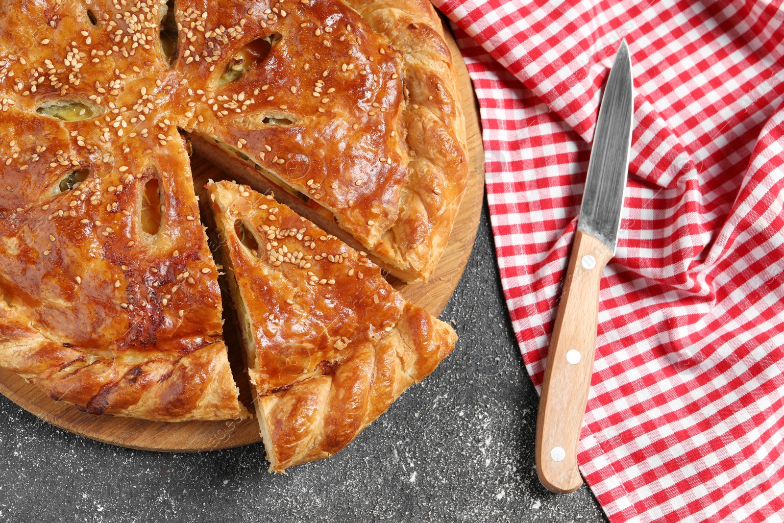 Photo of Cut delicious homemade pie and knife on black table, flat lay